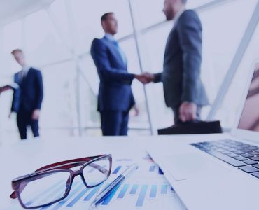 Business-shaking-hands-glasses-laptop-generic-stock